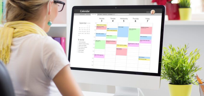 Woman using calendar app on computer in office- Time management tools for PhD students